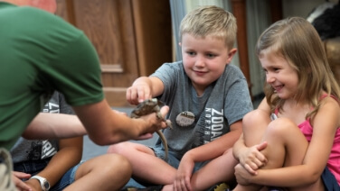 Children enrolled in ZooCamp encountering a lizard at ZooAmerica